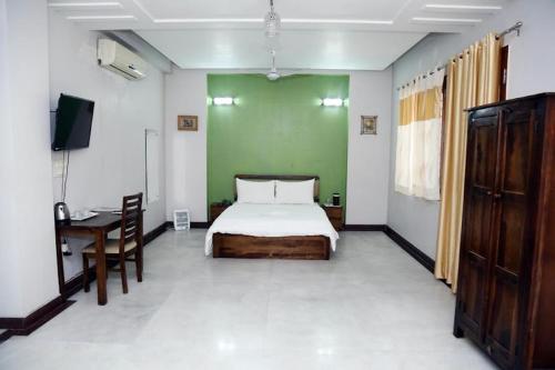 a bedroom with a bed and a desk with a television at Khushi residency in Greater Noida