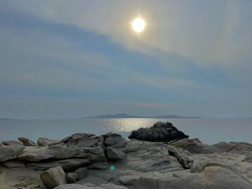 a moonrise over the water and rocks on a beach at Paradisiacal Villa with Pool and Sea View in Mykonos in Agios Ioannis Mykonos
