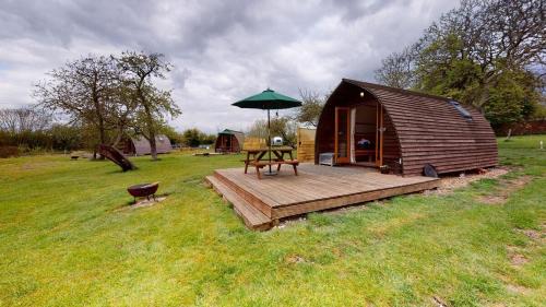 a small wooden cabin with a table and an umbrella at Hill Farm and Orchard in Leighton Buzzard