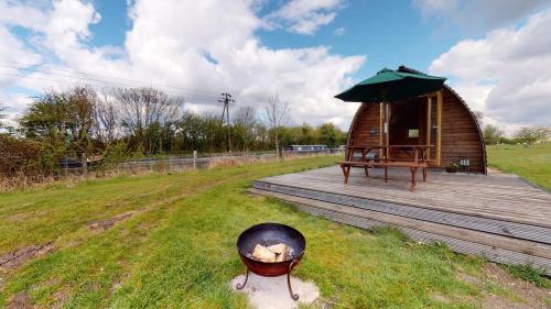 a small wooden cabin with a grill and an umbrella at Hill Farm and Orchard in Leighton Buzzard