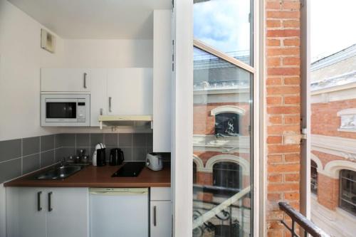 une cuisine avec des armoires blanches et une fenêtre dans l'établissement 405 - sejour romantique dans un studio de Paris 5, à Paris