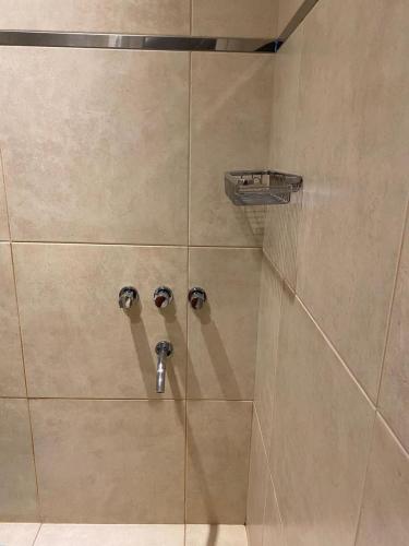 a shower with two knobs in a shower stall at Departamentos Recalada Suites in Monte Hermoso