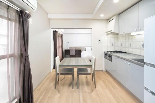 a table and chairs in a kitchen with white cabinets at HOTEL MYSTAYS Otemae in Osaka