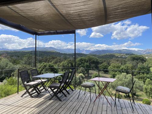 a deck with tables and chairs and a view of the mountains at A Casuccia in Zonza