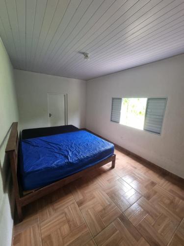a bedroom with a blue bed in a room with a window at Chácara Falcão in Itapeva