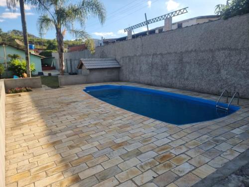 a swimming pool in a backyard with a stone wall at Chácara Falcão in Itapeva
