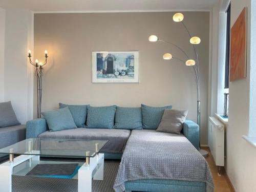 a living room with a blue couch and a glass table at Gemütliches Apartment, Seenähe, WM, WLAN, Balkon in Markkleeberg