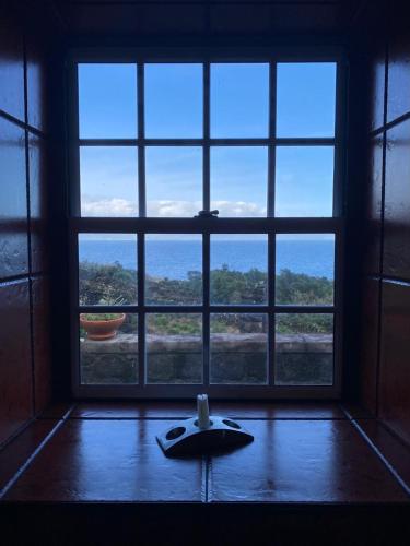 a room with a large window with a surfboard on the floor at Adega Baia do Canto AL 1398 in Terra Alta