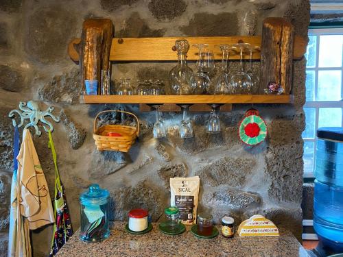 a counter with glasses on a stone wall at Adega Baia do Canto AL 1398 in Terra Alta