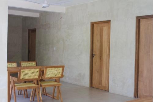 a dining room with a table and chairs and a door at Dannys Madiha in Godakanda