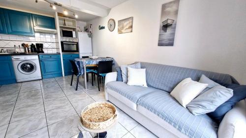 un salon avec un canapé bleu et une cuisine dans l'établissement A L AZURA Joli Duplex tout proche plage - Clim Wifi parking - Hameau de la Plage, à Saint-Cyprien