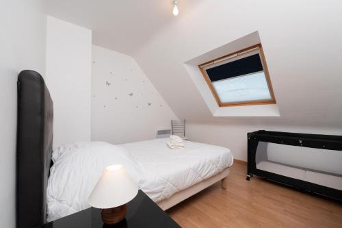a white bedroom with a bed and a window at Maison Familiale moderne 5p in Sainte Anne d'Auray 