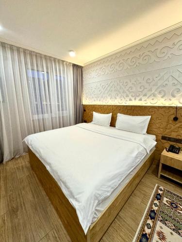 a bedroom with a large bed with white sheets at Dami Almaty Hotel in Almaty