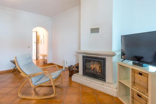 a living room with a fireplace and a tv at PÉ NA AREIA by Stay in Alentejo in Vila Nova de Milfontes