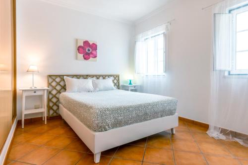 a white bedroom with a bed and two windows at PÉ NA AREIA by Stay in Alentejo in Vila Nova de Milfontes