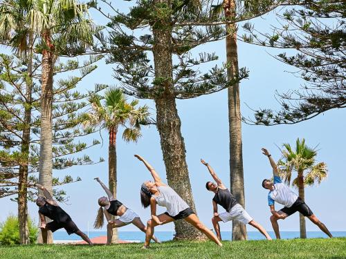 a group of people doing a yoga pose in the grass at Grecotel LUXME White in Adelianos Kampos