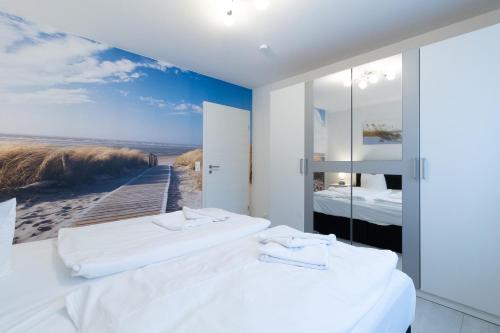 two beds in a room with a painting of a beach at Haus am Großbahnhof Whg. 2 in Binz