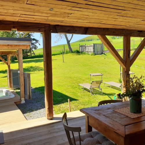 a wooden deck with a table and chairs and a field at Vila Harmónia in Lúčka