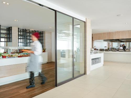 a man walking past a kitchen in a building at Grecotel LUXME White in Adelianos Kampos