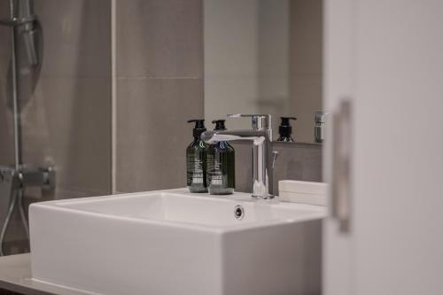 a bathroom sink with a faucet and bottles on it at 1Bedroom Apartment Oak Luxury by Blue Cloud Holidays in Sharjah