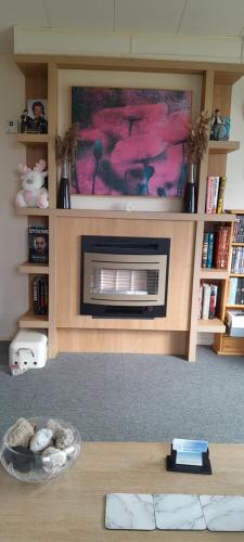 a living room with a fireplace and a table at Arual Caravan Manor House Park. Allonby, Cumbria in Maryport