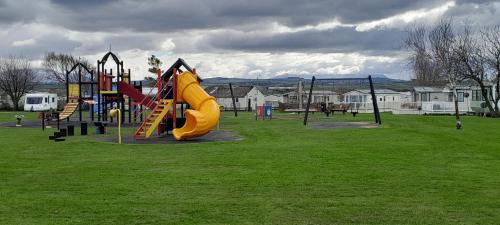 a playground with a yellow slide in a park at Arual Caravan Manor House Park. Allonby, Cumbria in Maryport
