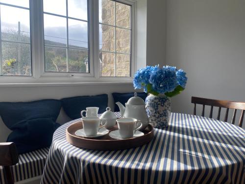 a table with a plate with tea sets on it at Garden Flat in West Lulworth in West Lulworth