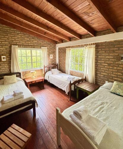 a bedroom with two beds and two windows at Casa de Mimbres in El Calafate