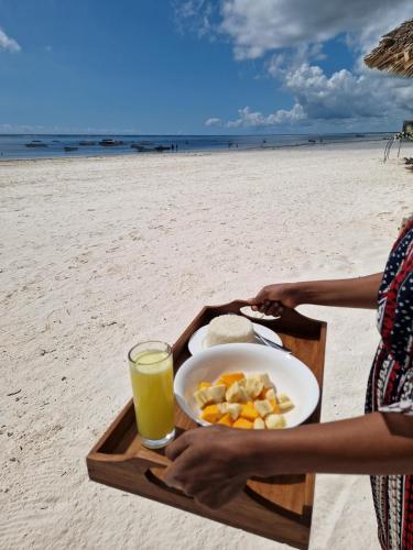 a tray of food and a drink on the beach at Just Heaven Apartments in Matemwe