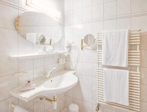 a white bathroom with a sink and a mirror at Hotel Magdalena Mayrhofen in Mayrhofen