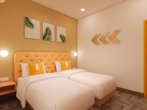 a bedroom with two beds with yellow and orange pillows at Bloom Hotel - Taloja, Navi Mumbai in Panvel