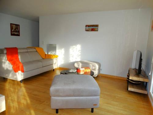 - un salon avec un canapé et un pouf dans l'établissement Appartement Saint Gilles Croix de Vie - Alizé, à Saint-Gilles-Croix-de-Vie
