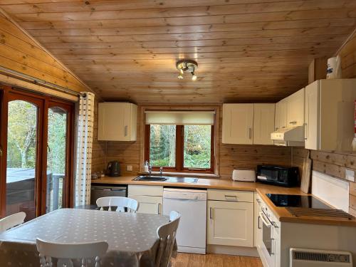 a kitchen with a table and chairs in a cabin at Cuckoo Lodge - Arscott Lodges in Great Hanwood