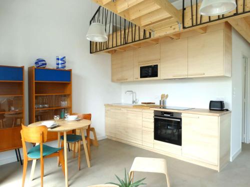 une cuisine avec des armoires en bois et une table et des chaises dans l'établissement Hélios Saint Gilles Croix de Vie, à Les Bussolleries