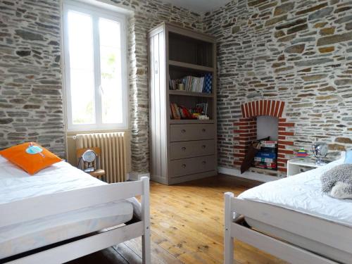 une chambre avec deux lits et un mur de briques dans l'établissement Hippocampe Saint Gilles croix de Vie, à Les Bussolleries