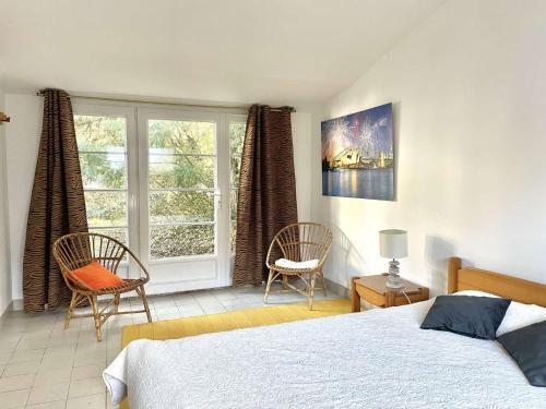 une chambre avec un lit et deux chaises et une fenêtre dans l'établissement Les Trolls Saint Hilaire de Riez, à Sion-sur-lʼOcéan