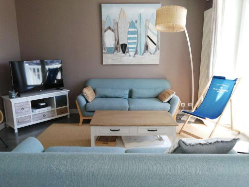 un salon avec un canapé bleu et une télévision dans l'établissement Quatre Vents Saint Hilaire de Riez, à Saint-Hilaire-de-Riez