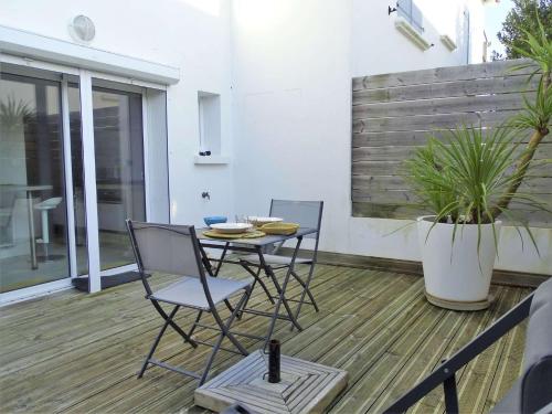 une terrasse avec 2 chaises, une table et une plante dans l'établissement Dauphin Saint Gilles Croix de Vie, à Les Bussolleries