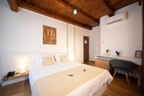 a bedroom with a large white bed and a desk at Rooms Natura in Vilanija