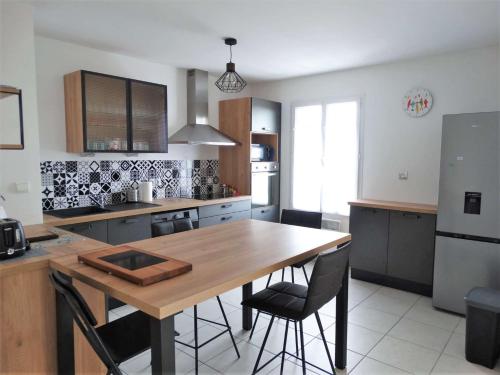 a kitchen with a wooden table and some chairs at Gardénia Saint Gilles Croix de Vie in Le Sablais