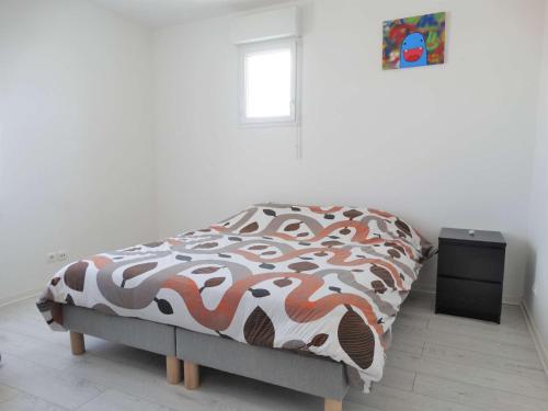 a bedroom with a bed with a comforter and a window at Gardénia Saint Gilles Croix de Vie in Le Sablais