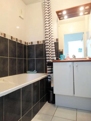 une salle de bain avec une baignoire, un lavabo et un miroir dans l'établissement Gardénia Saint Gilles Croix de Vie, à Le Sablais