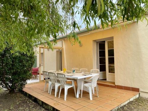 une table blanche et des chaises sur une terrasse dans l'établissement Flotteur, à Saint-Hilaire-de-Riez