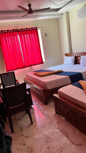 a room with three beds and a window with red curtains at The Fortune inn in Chennai