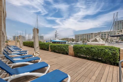 a row of blue lounge chairs on a deck at Luxury Modern Apt on the beach in Herzliyya B