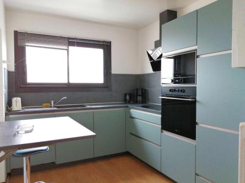 La cuisine est équipée de placards bleus et d'un four avec plaques de cuisson. dans l'établissement Goélette Saint Gilles Croix de Vie, à Le Sablais