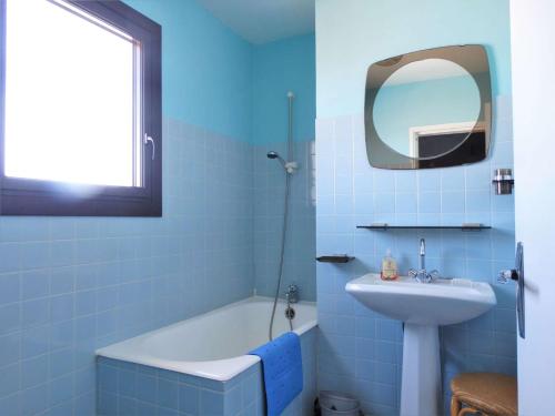 a blue bathroom with a tub and a sink and a mirror at Goélette Saint Gilles Croix de Vie in Le Sablais