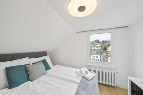a white bed in a room with a window at book2stay - Apartments Herisau in Herisau
