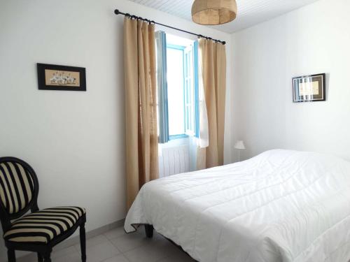 une chambre avec un lit, une chaise et une fenêtre dans l'établissement Hauban - Saint Gilles Croix de Vie, à Saint-Gilles-Croix-de-Vie