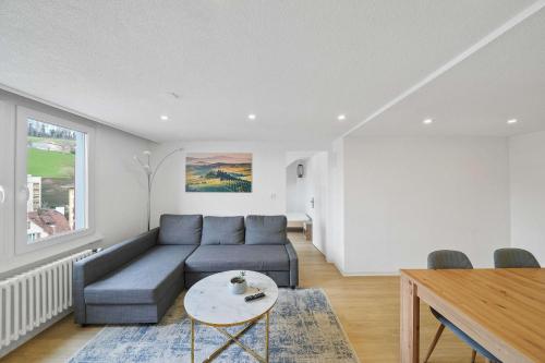 a living room with a blue couch and a table at book2stay - Apartments Herisau in Herisau